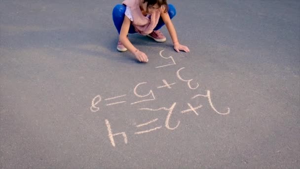 Barnet skriver matte på trottoaren. Selektiv inriktning. — Stockvideo