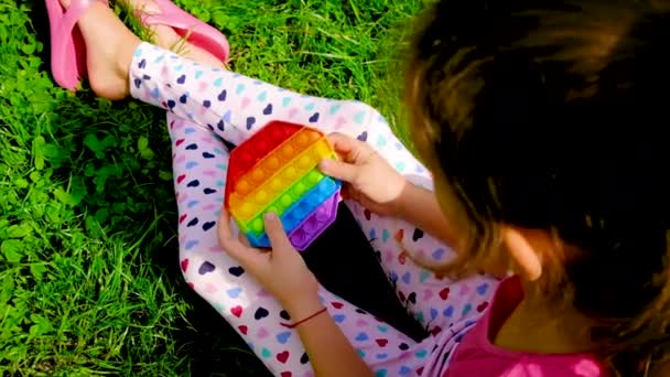 The child plays anti-stress pop it in his hands. Selective focus. — Stock Video