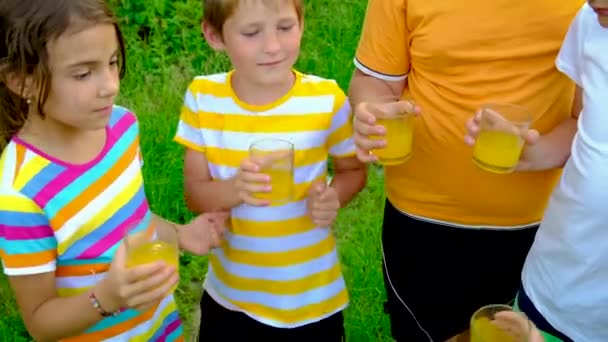 Les enfants boivent de la limonade dans un verre ensemble. Concentration sélective. — Video