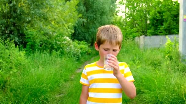 The child drinks water from a glass. Selective focus. — Stock Video