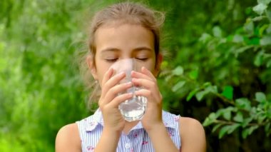 Çocuk kız bardaktan su içer. Seçici odak.