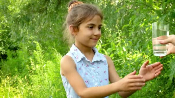 La niña bebe agua de un vaso. Enfoque selectivo. — Vídeos de Stock