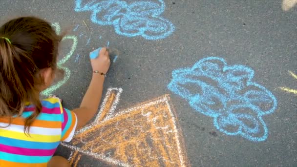 아이는 아스팔트에 분필로 그림을 그립니다. 선택적 초점. — 비디오