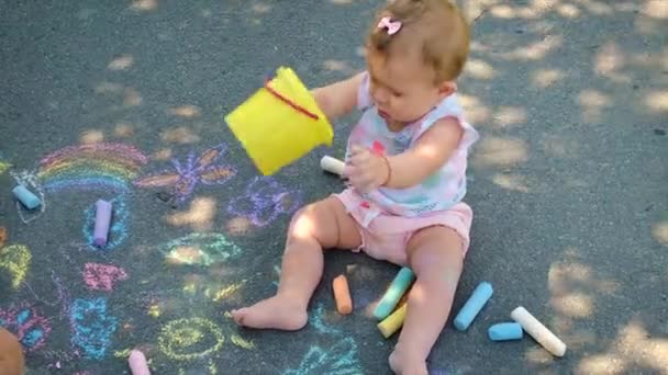 Barnet ritar med krita på asfalten. Selektiv inriktning. — Stockvideo