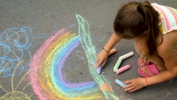 Το παιδί ζωγραφίζει ένα ουράνιο τόξο με κιμωλία. Επιλεκτική εστίαση. — Αρχείο Βίντεο