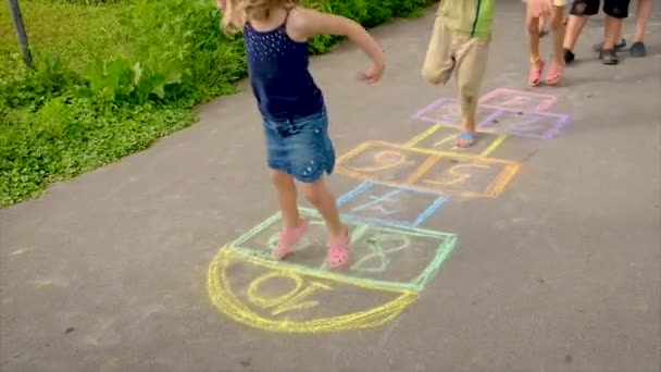 Les enfants jouent des classiques sur l'asphalte. Concentration sélective. — Video