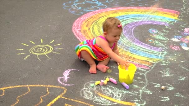 Barnet ritar en regnbåge med krita. Selektiv inriktning. — Stockvideo