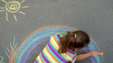 Çocuk tebeşirle bir gökkuşağı çiziyor. Seçici odak.