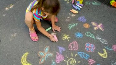 Çocuk asfalta tebeşirle çizer. Seçici odak.