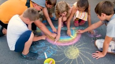 Çocuk tebeşirle bir gökkuşağı çiziyor. Seçici odak.