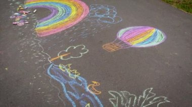 Çocuk tebeşirle bir gökkuşağı çiziyor. Seçici odak.