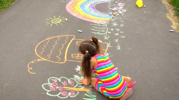 L'enfant dessine à la craie sur l'asphalte. Concentration sélective. — Video