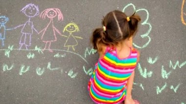 Çocuk tebeşirle bir gökkuşağı çiziyor. Seçici odak.