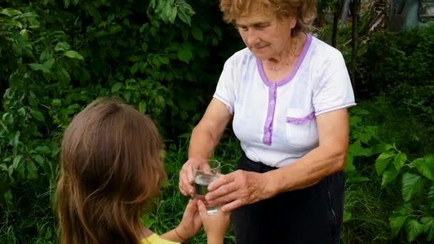 Ребенок дает стакан воды бабушке. Селективный фокус. — стоковое видео
