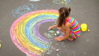 Çocuk tebeşirle bir gökkuşağı çiziyor. Seçici odak.