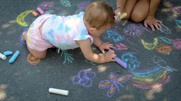 L'enfant dessine à la craie sur l'asphalte. Concentration sélective. — Video