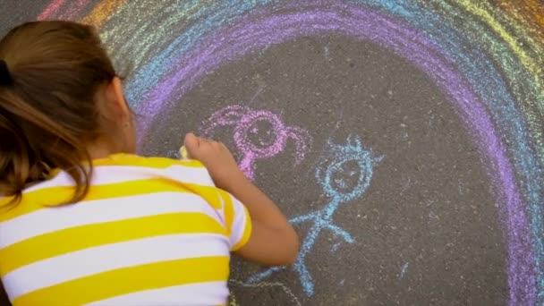 Los niños dibujan con tiza sobre el asfalto. Enfoque selectivo. — Vídeos de Stock