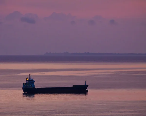 Силуэт танкового корабля пришвартовался на якоре против красного закатного неба — стоковое фото