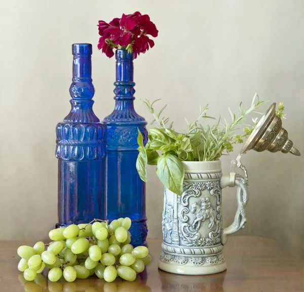 İki mavi şişe, üzüm ve otlar