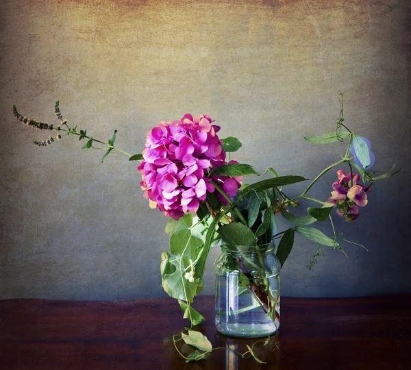 Grunge ve vintage etkileri ile cam vazoda ortanca