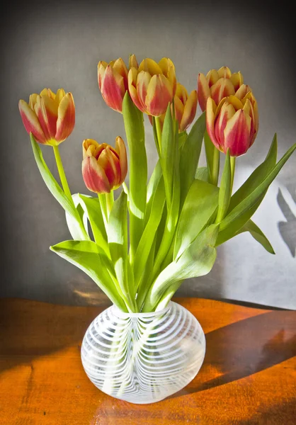 Skleněná váza s tulipány na dřevěný stůl — Stock fotografie