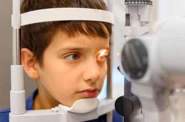 Göz muayenesi yapılan çocuğun göz muayenesi sırasında göz hekiminde açık görüş kontrolü için kesik lamba kullanılıyor.