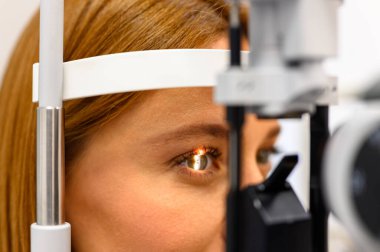 Klinikteki gözüne odaklanmış kesik lamba ışığıyla göz muayenesinden geçen kadın hastaya yakından bakın.