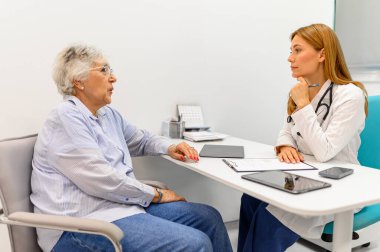 Kıdemli kadın klinikteki danışmanlık sırasında kadın doktora semptomlarını ve sağlık sorunlarını anlatıyor.