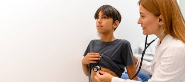 Kalp atışlarını steteskopla dinleyen kadın doktor, rutin sağlık değerlendirmesi için hastanede hastayı muayene ederken...