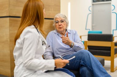 Üst düzey kadın, rutin kontroller sırasında kadın doktorla semptomları tartışıyor ve not alıyor.