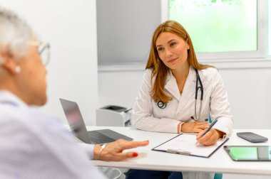 Hastanedeki kıdemli hastayla konuşurken panoya teşhis koyan kadın göz doktoru.