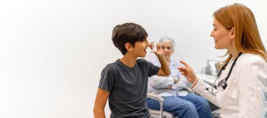 Büyükannem, çocuk kliniğine rutin bir ziyarette küçük bir çocuğa astım pompasını nasıl kullanacağını öğreten kadın doktora bakıyor.