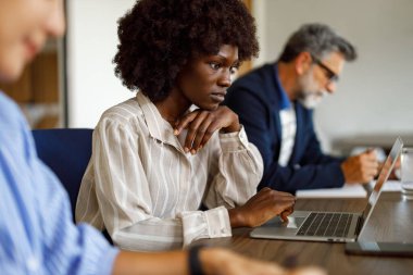 Modern ofiste meslektaşımla otururken bilgisayardaki mali raporları analiz eden ciddi bir muhasebeci.