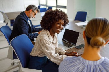 Ofiste çalışan bir iş kadınının, kadın meslektaşıyla konuşurken gülümseyişine yüksek açılı bir bakış açısı
