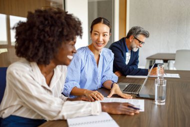 Kadın muhasebeciler, arka planda iş adamıyla modern yönetim kurulunda yapılan toplantı sırasında mali raporları tartışıyorlar.