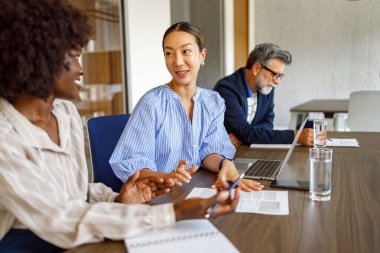 Profesyonel toplantı sırasında arka planda iş adamıyla birlikte kadın ortaklar stratejileri tartışıyor.