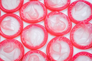 Beyaz arka planda pembe prezervatiflerin üst görüntüsü. Güvenli seks kavramı. Hamileliğin azaltılması ve cinsel yolla bulaşan hastalıklar.