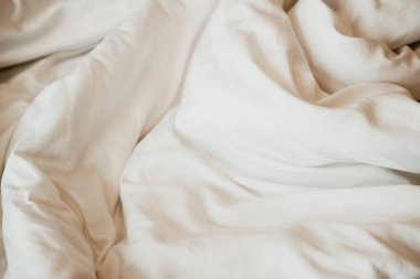 Beyaz yorganın üstünde güneş ışığı olan bir yatak. Beyaz yataklı yatak odası..