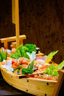 Suşi sashimi kahverengi ahşap bir masada ahşap bir teknede. Melodi, karides, karides, zencefil