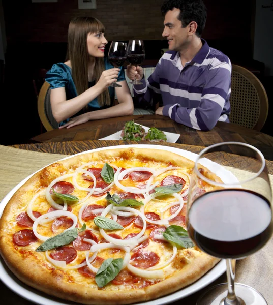 Pareja bebiendo vino y comiendo pizza — Foto de Stock