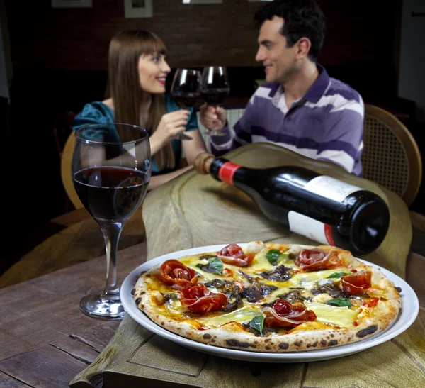 Couple drinking wine and eating pizza — Stock Photo, Image