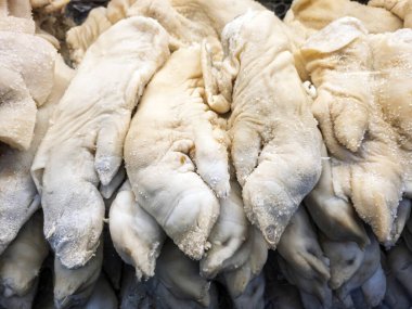 Market vitrininde asılı korunmuş ya da tuzlanmış domuz paçaları satışa hazır.