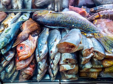 Gümüş pullu, parlak gözlü taze çiğ balıkları bir market tezgahında satılığa çıkar.