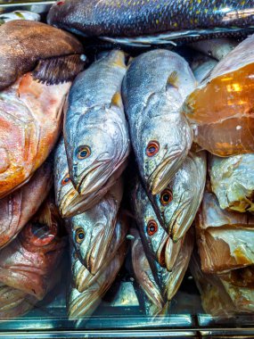 Gümüş pullu, parlak gözlü taze çiğ balıkları bir market tezgahında satılığa çıkar.
