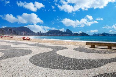 Copacabana sahil şeridine bakan ünlü dalga desenli mozaik, kumlu sahil şemsiyeleri, ve Sugarloaf Dağı bölgesi, Rio de Janeiro, Brezilya.
