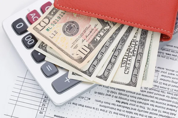 Argent en portefeuille et calculatrice sur fond de formulaire d'impôt — Photo