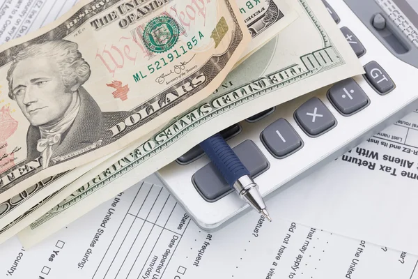 Money and pen with calculator on tax form background — Stock Photo, Image