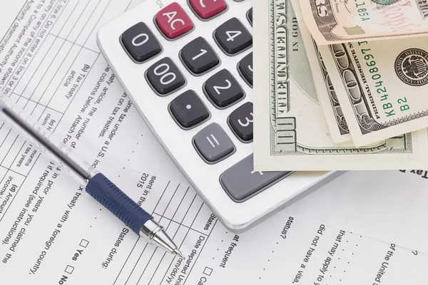 Dinero y pluma con calculadora en el fondo del formulario de impuestos —  Fotos de Stock