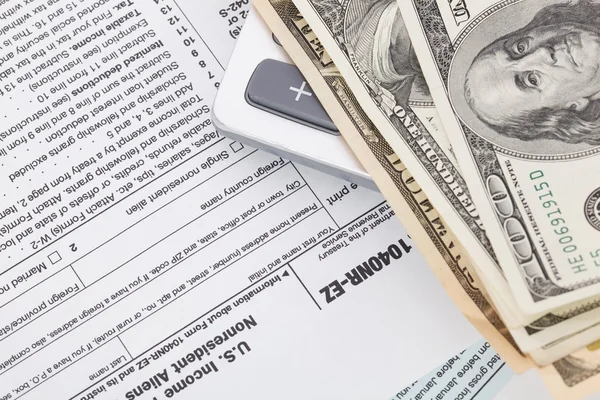 Dinero y calculadora en el fondo del formulario de impuestos — Foto de Stock