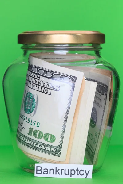 Money in glass jars, on Green background with sign - Bankruptcy